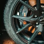 Detailed photo of a black alloy wheel with visible water droplets and a prominent Brembo brake caliper.